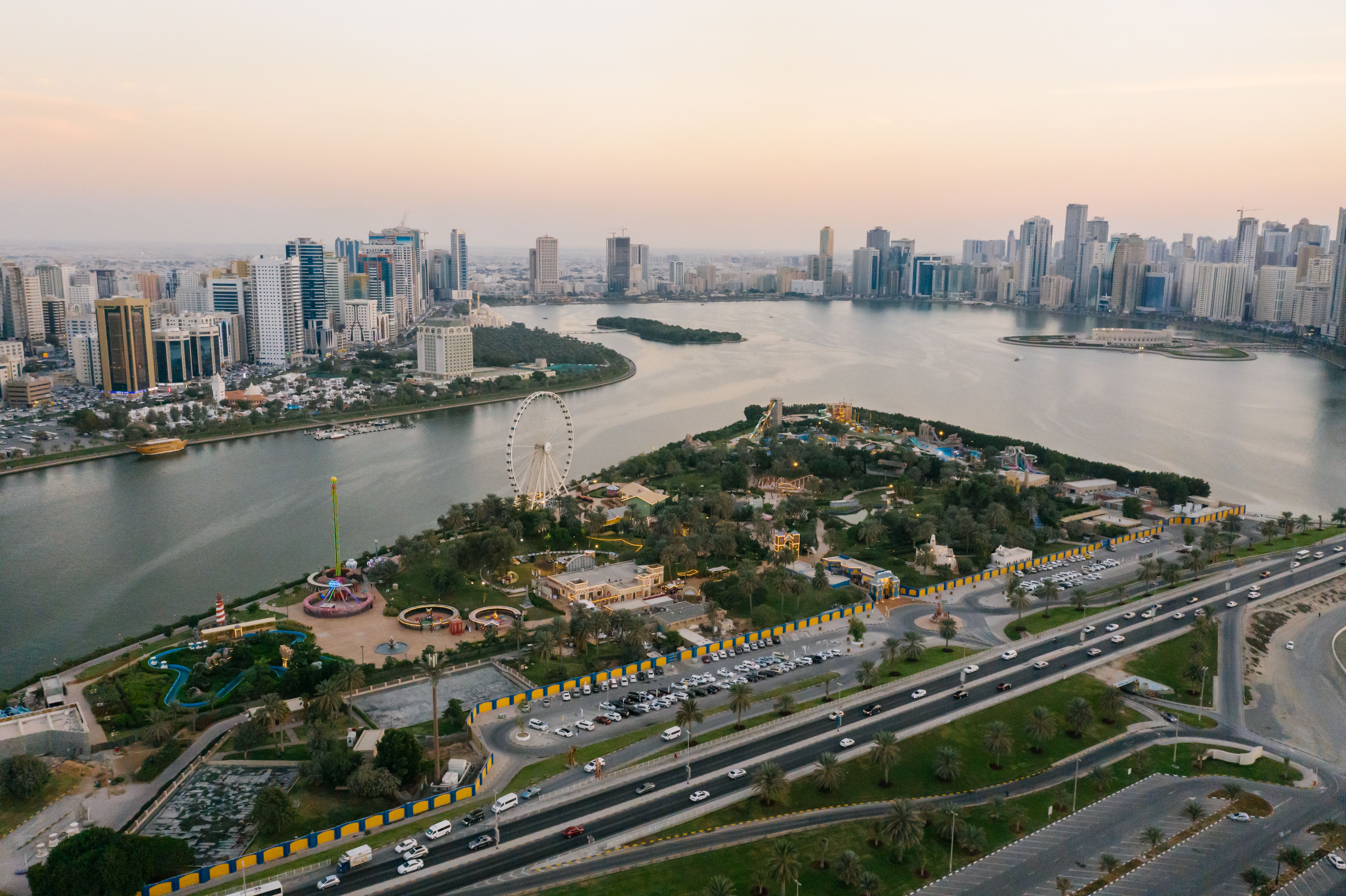 Aerial view of Sharjah's urban landscape showing roads, waterfront, and high-rise buildings, highlighting infrastructure development and the importance of land surveying, GIS mapping, and urban planning in the UAE.